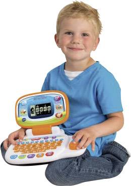 Ein Kind sitzt auf dem Boden und hält einen bunten Spielzeug-Laptop in den Händen, lächelnd in die Kamera.