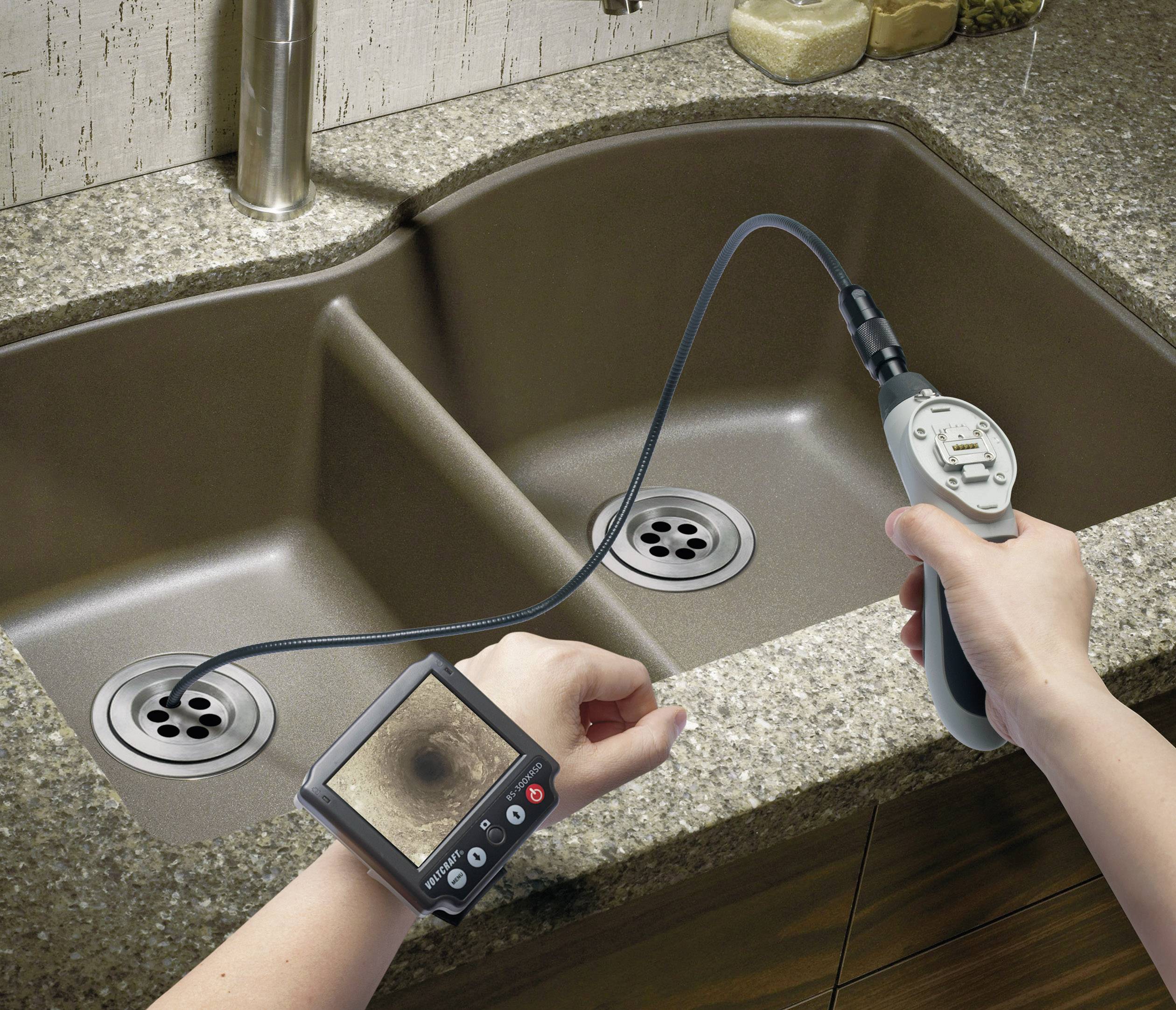 Person benutzt Inspektionskamera mit Monitor, um Abfluss unter Spüle zu überprüfen. Gerät zeigt das Innere des Rohrs.