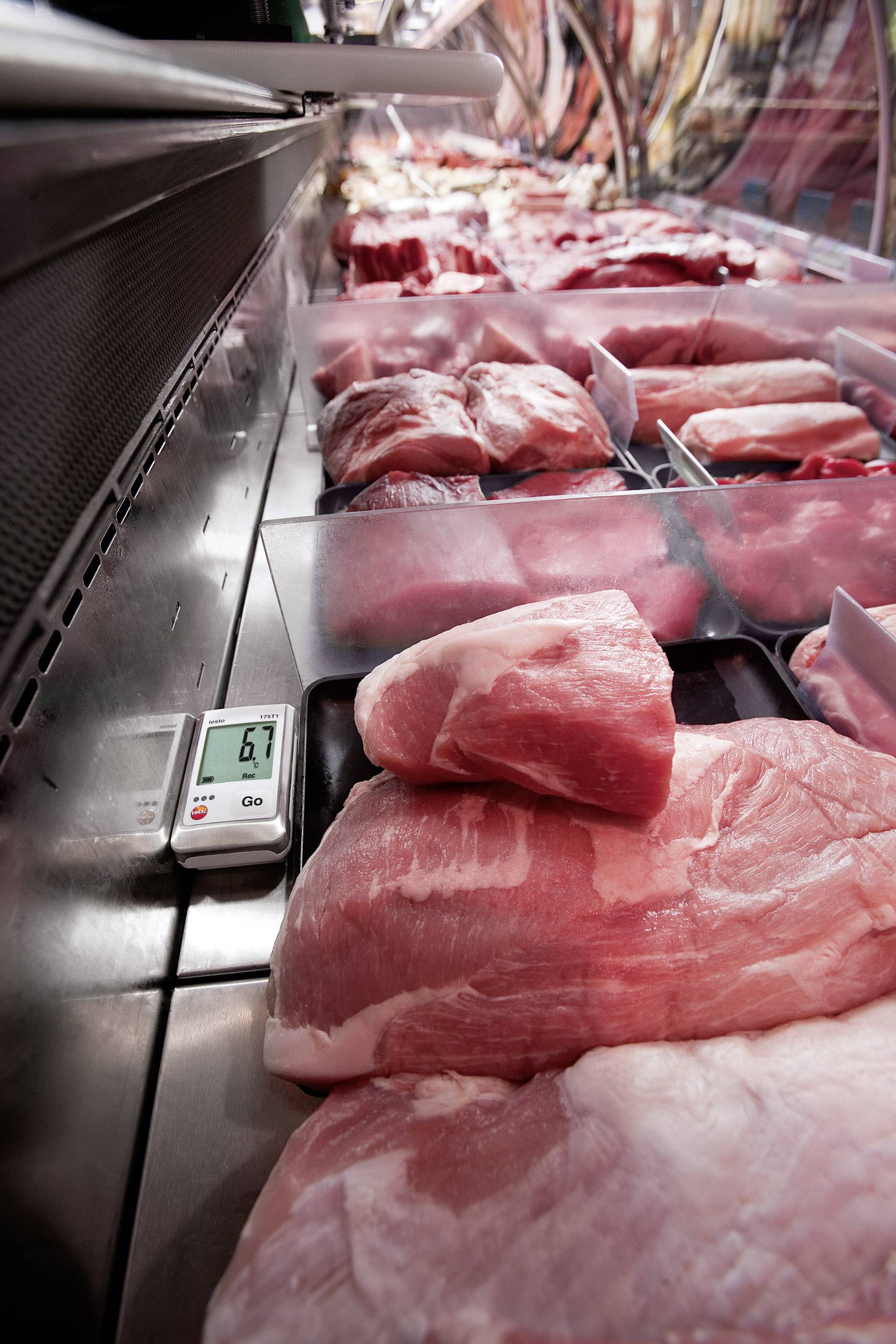 Frisches Fleisch liegt in einer Metzgertheke. Ein Thermometer zeigt 6,9 Grad Celsius an, um die Lagerungstemperatur anzuzeigen.