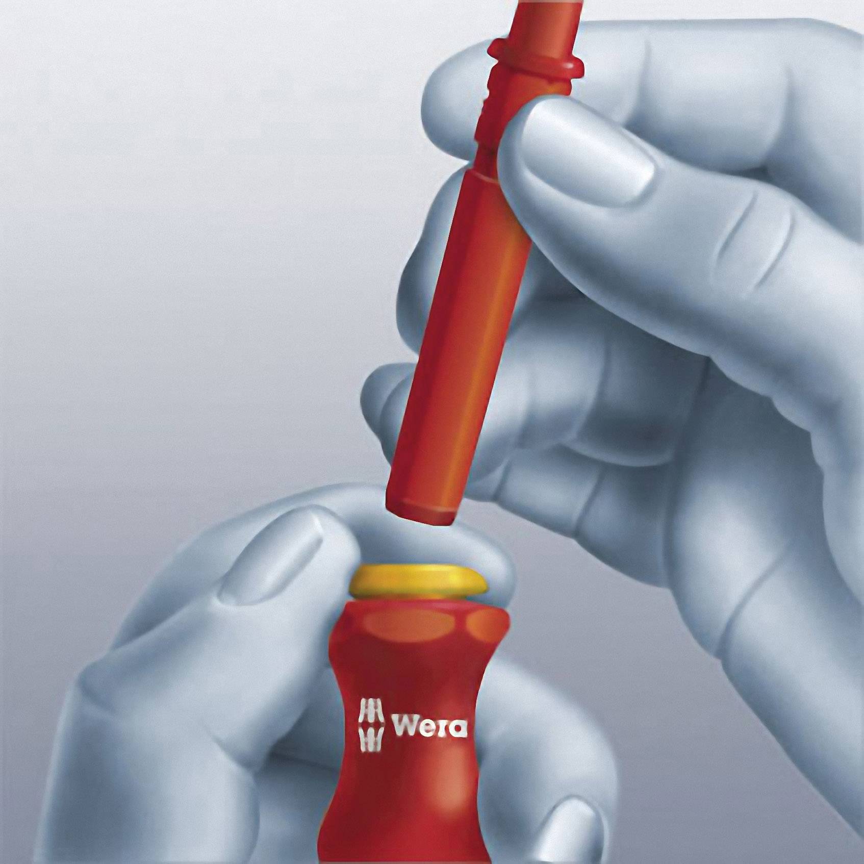 Eine Hand hält einen Schraubendreher von Wera, der in einem roten Halter steckt.
