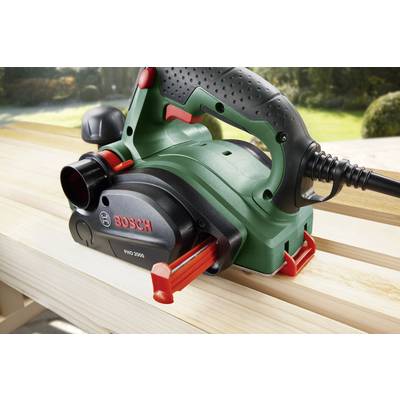 Elektrischer Handhobel auf einem Holztisch; das Gerät ist grün mit roten Akzenten und trägt die Aufschrift 'Bosch PHO 2000'.
