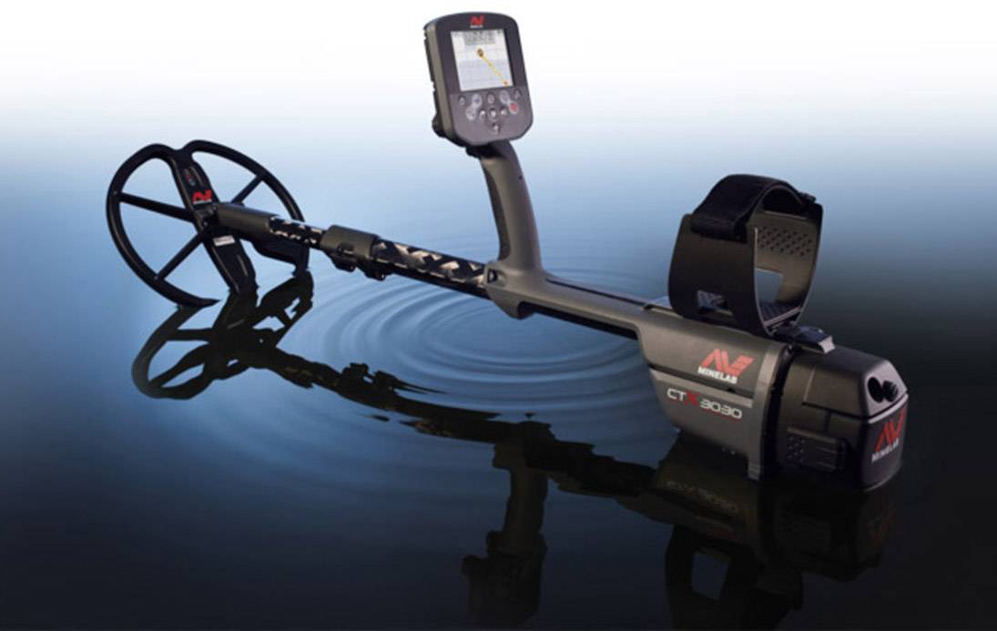 Ein Metalldetektor steht halb im Wasser. Der Detektorkopf ist im Vordergrund, das Display zeigt eine einfache Grafikanzeige.