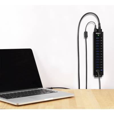 Ein Laptop ist mit einem USB-Hub verbunden, der an der Wand montiert ist; mehrere USB-Anschlüsse und Kabel sind sichtbar.