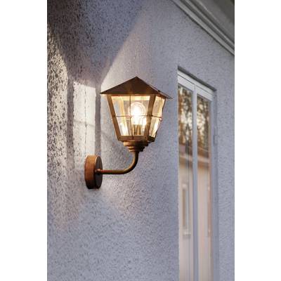 Eine eingeschaltete Wandlampe mit Glühbirne leuchtet an einer Außenwand neben einem Fenster.