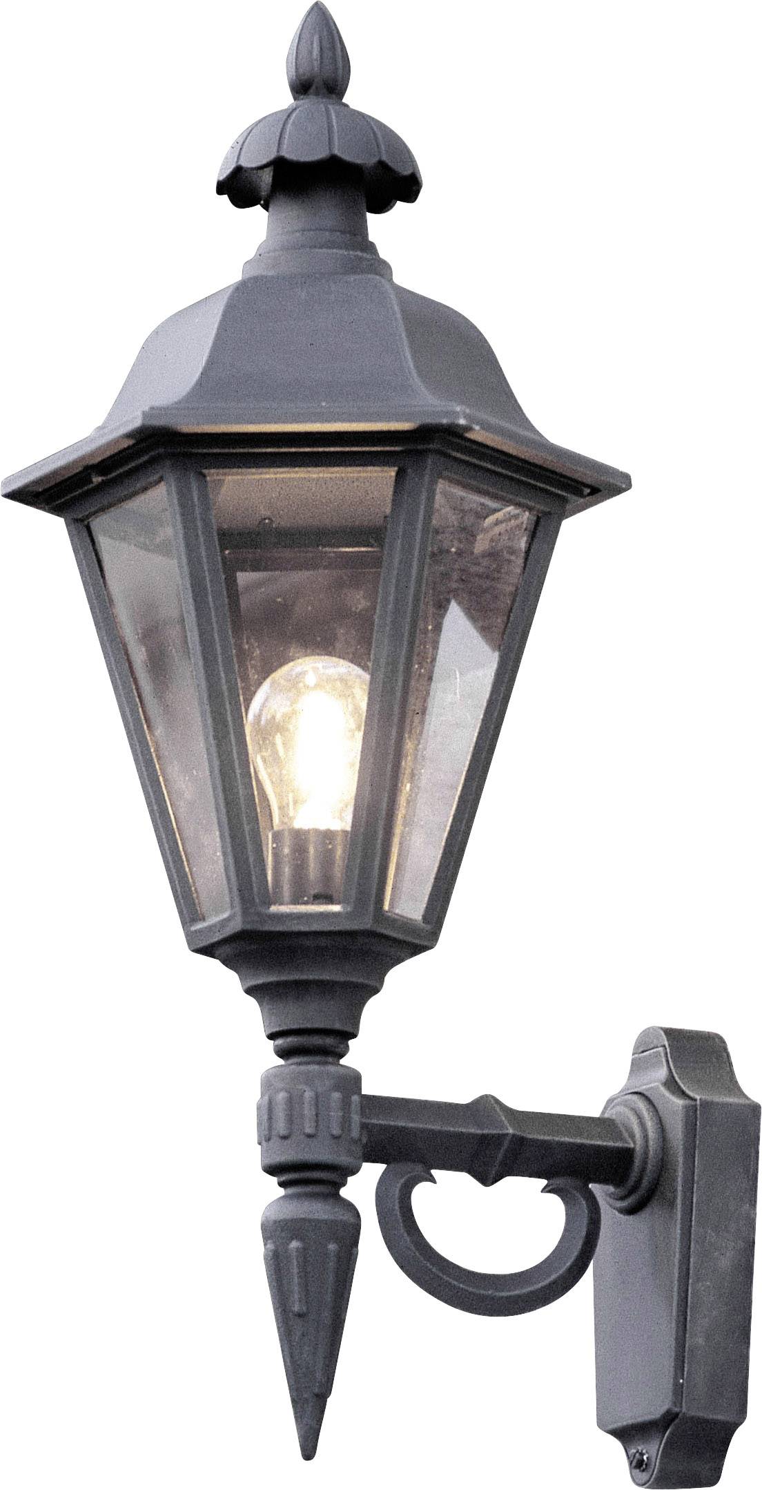 Schwarze Außenwandleuchte im antiken Stil mit gläsernem Lampenschirm. Die Lampe ist eingeschaltet und leuchtet warm.