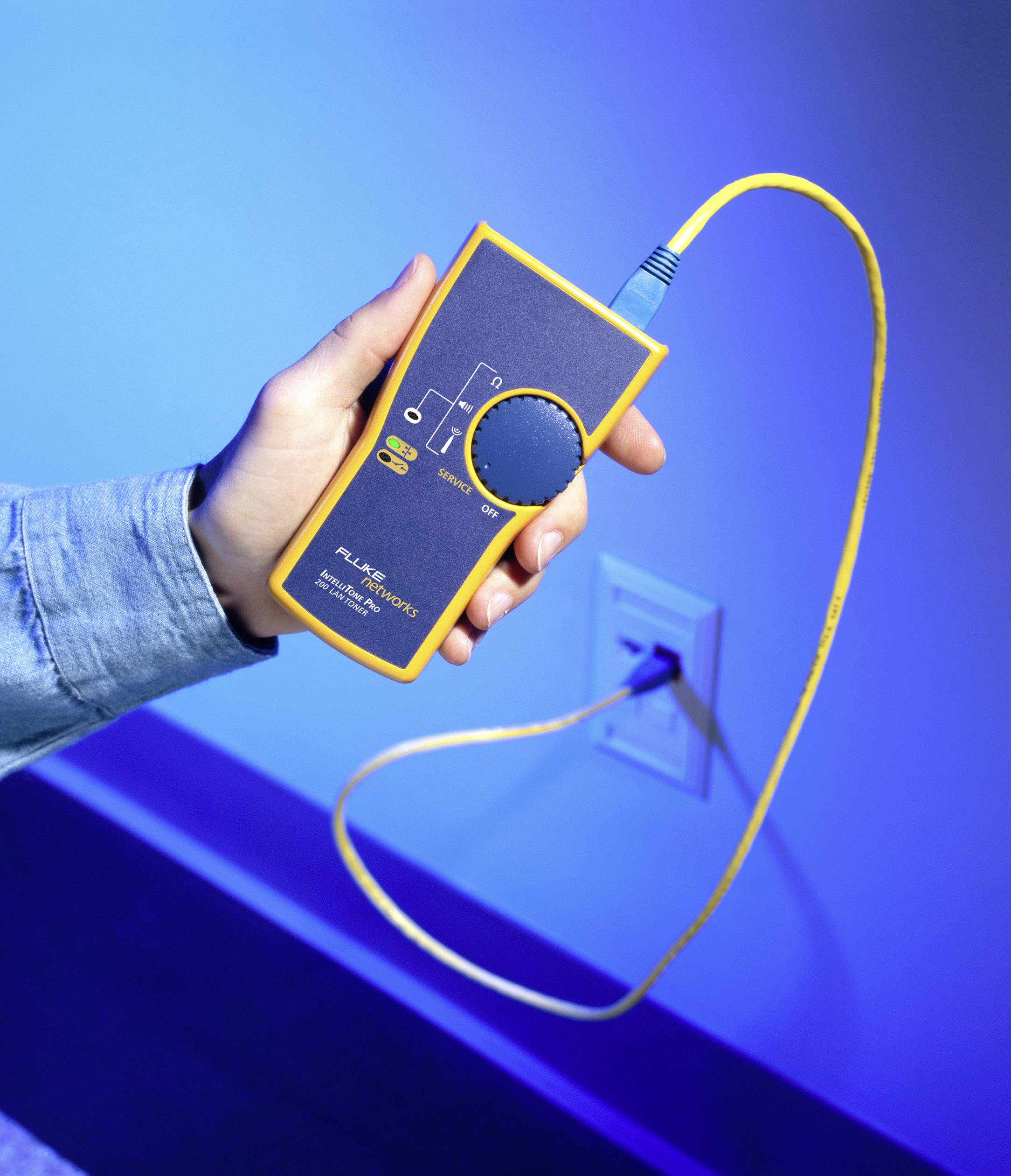 Eine Person hält ein gelbes Netzwerk-Kabeltestergerät vor einer blauen Wand. Das Gerät dient zur Diagnose von Netzwerkverbindungen.