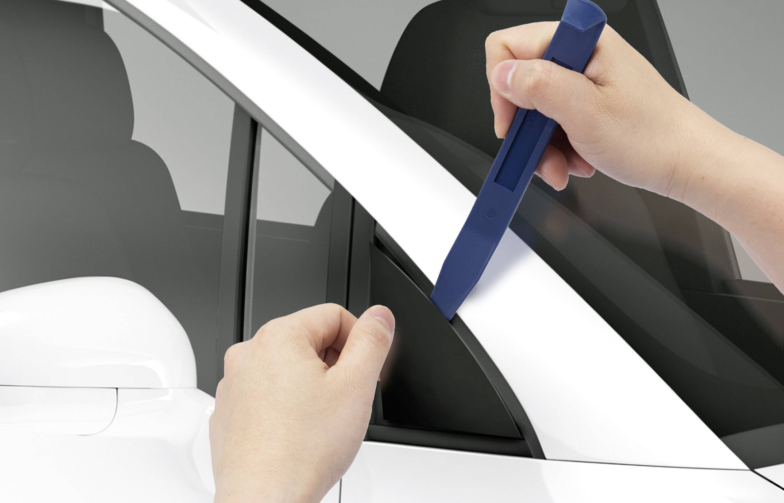 Person benutzt blaues Werkzeug, um Autotür zu öffnen. Fokus auf Werkzeug und Fahrzeugteil. Szenario deutet auf Autoreparatur oder Wartung hin.