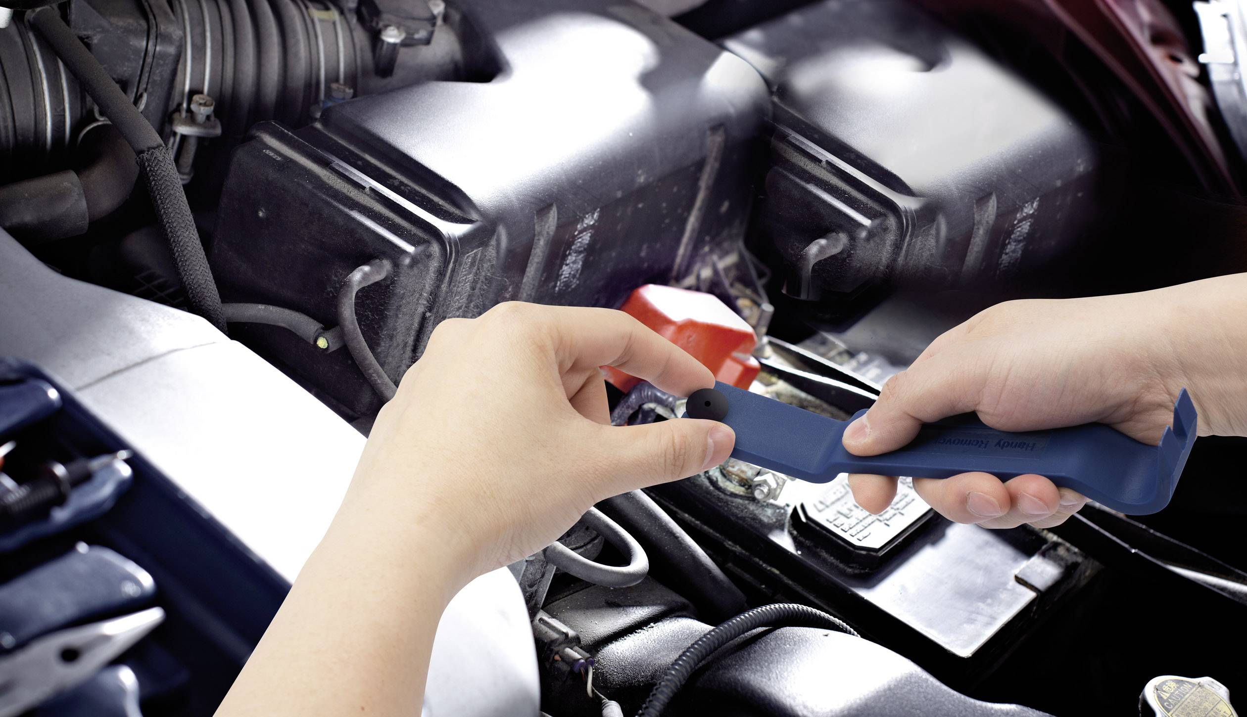 Eine Person prüft den Motor eines Autos mit einem Schraubenschlüssel, Fokus liegt auf der Handbewegung und den Motordetails.