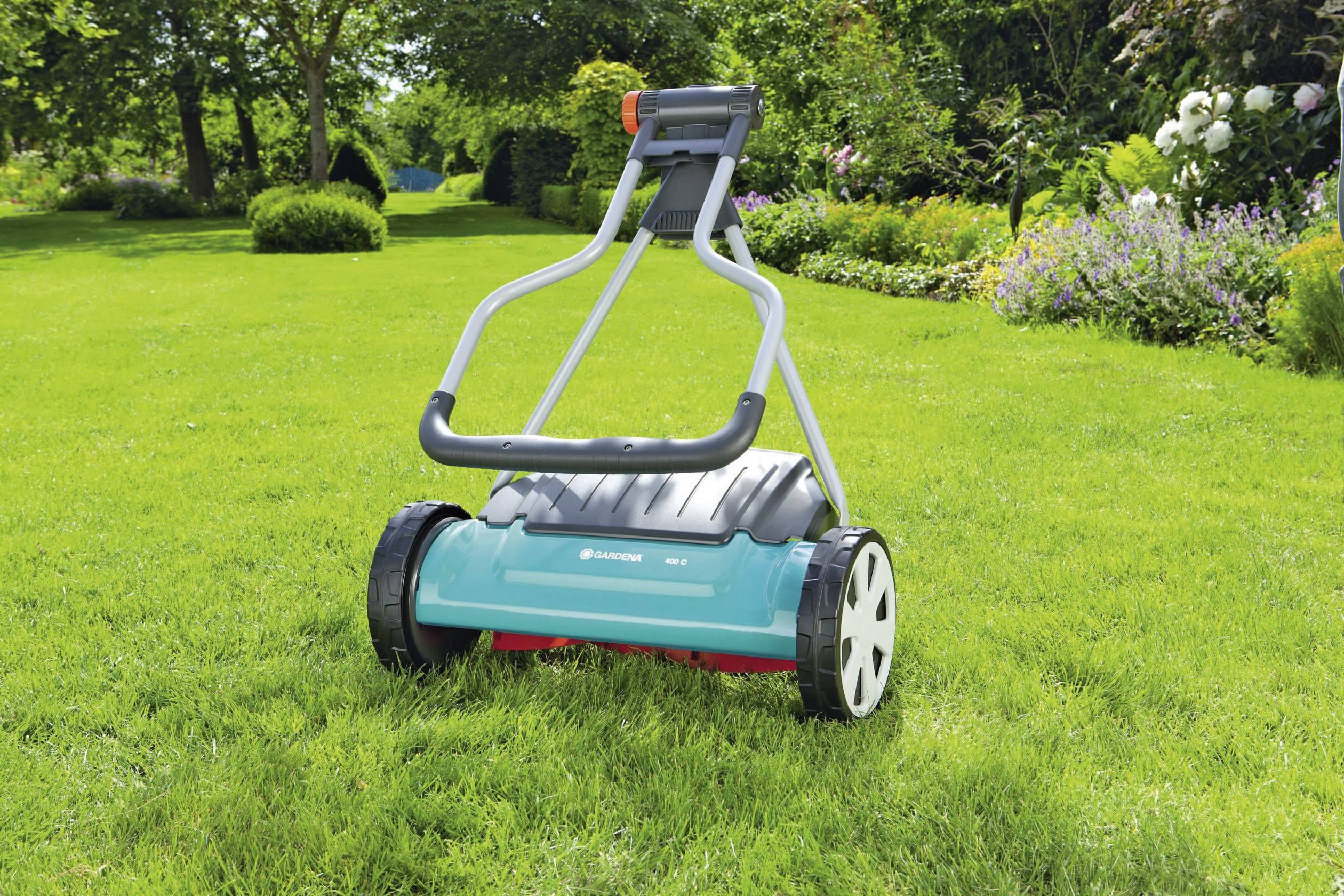 Rasenmäher im grünen Garten, umgeben von Büschen und Bäumen, bereit zum Einsatz im gepflegten, sonnigen Außenbereich.
