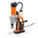 Eine orange und graue Magnetbohrmaschine mit Griff und Kabel, stehend auf einer flachen Oberfläche.