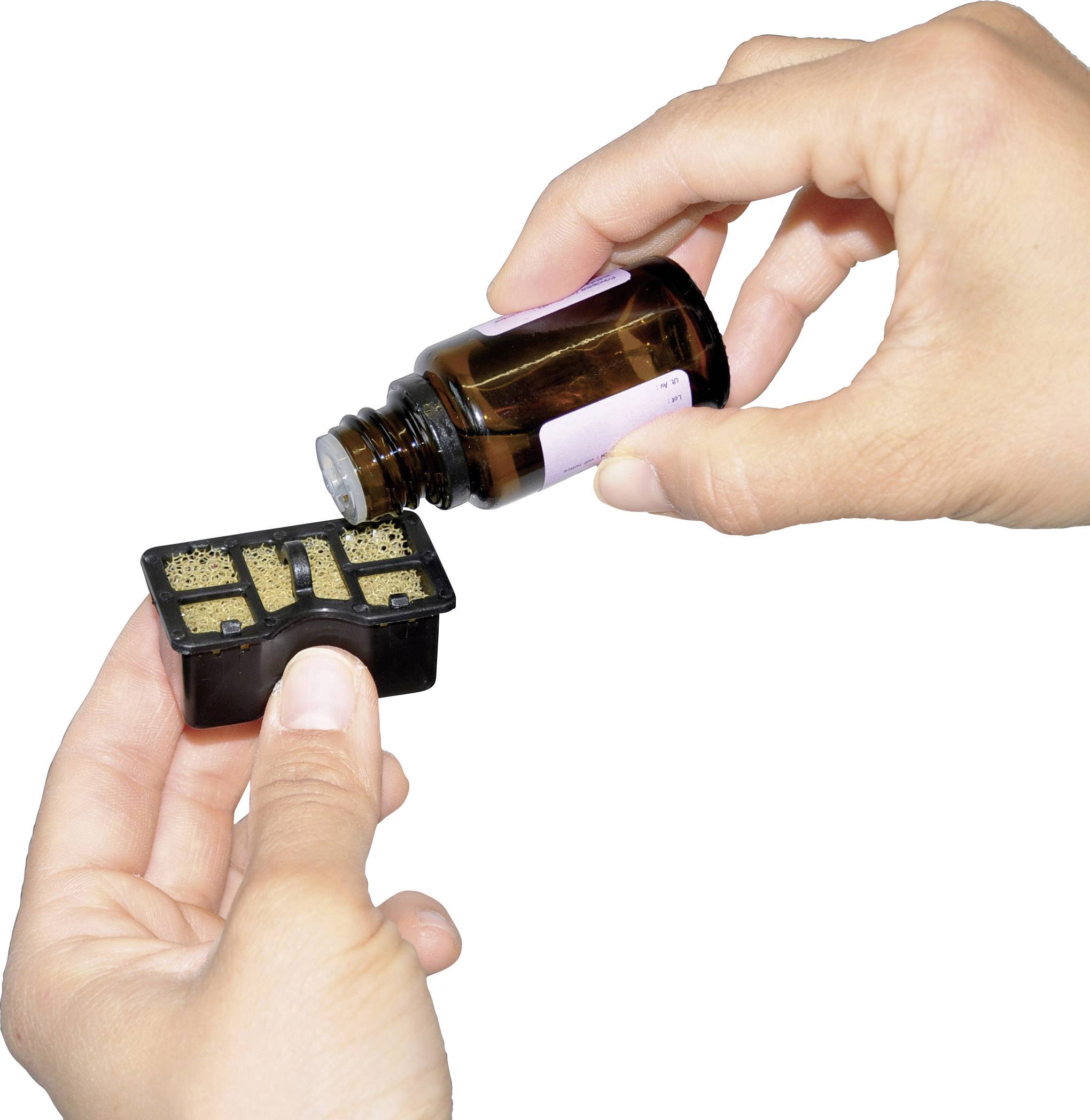 Eine Person hält eine braune Glasflasche und füllt Flüssigkeit in ein kleines schwarzes Behältnis mit Fächern.