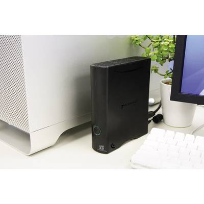 Externe Festplatte neben einem Computer, mit Pflanzen in der Nähe; dient zur Datenlagerung und Backup-Erweiterung.