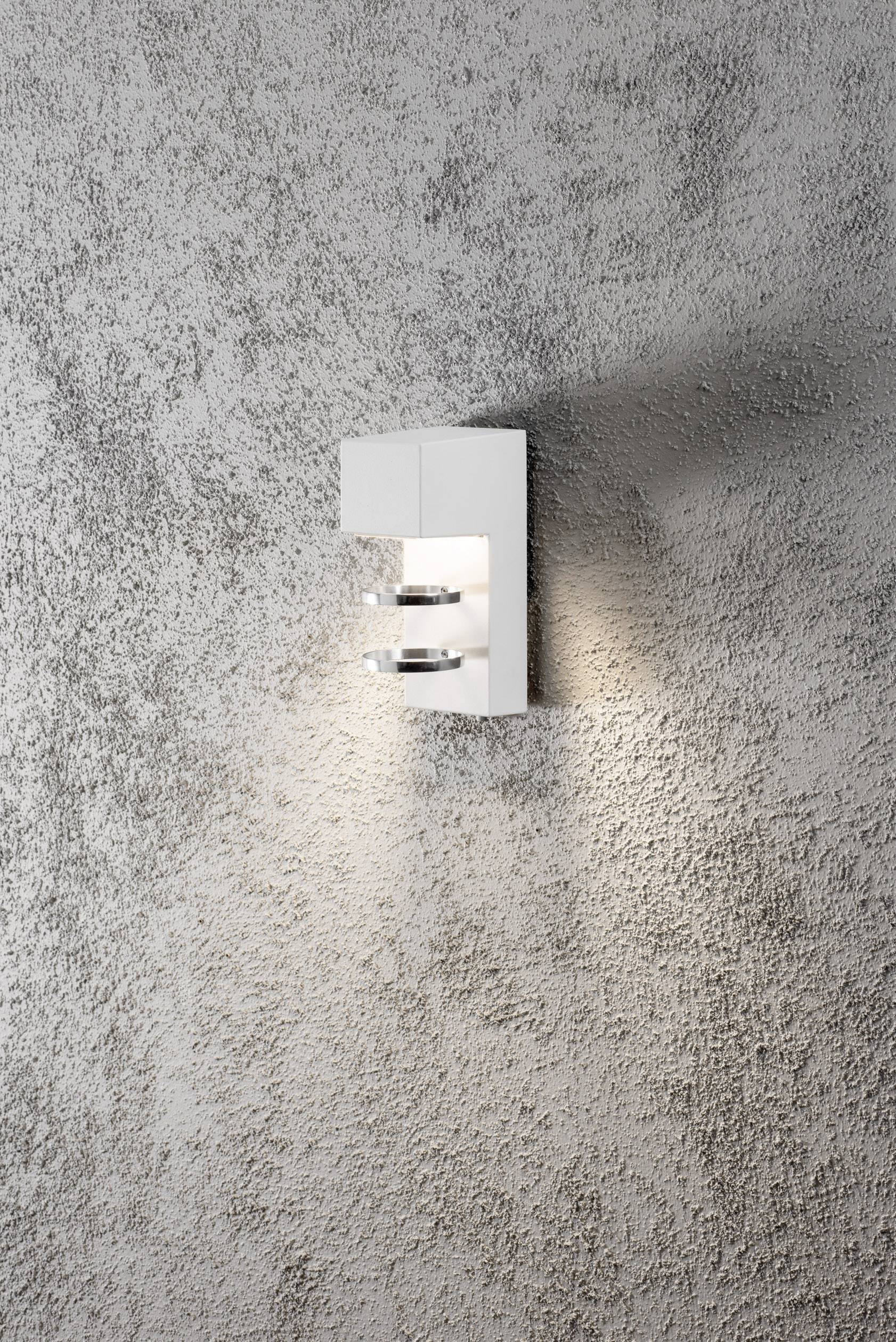 Wandleuchte mit modernem Design, rechteckiger, weißer Körper aus Metall, montiert auf strukturierter, grauer Wand, beleuchtet umgebung.