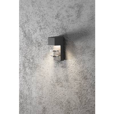Eine moderne Wandleuchte mit rechteckigem Gehäuse strahlt warmes Licht an eine raue graue Wand.