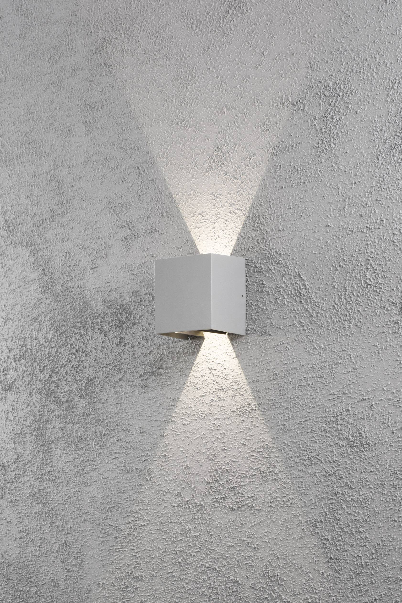 Wandleuchte mit modernem Design, die nach oben und unten strahlt, auf strukturierten grauen Wand montiert.