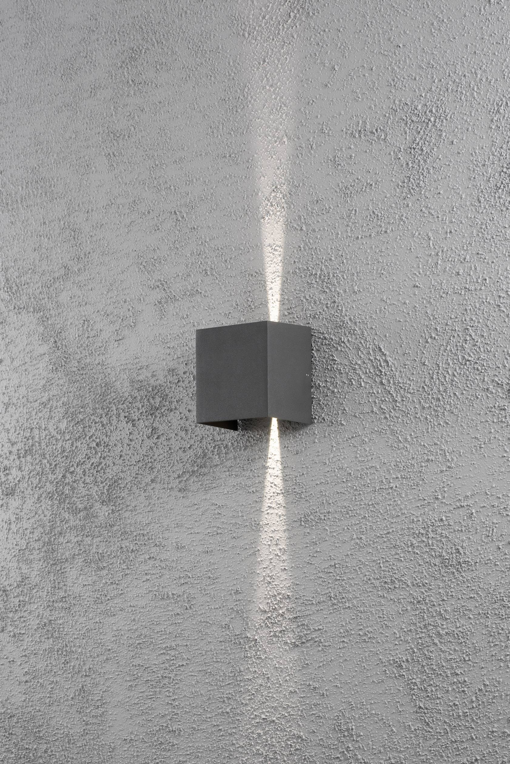 Wandleuchte auf grauer Wand, strahlt Licht nach oben und unten, erzeugt einen dekorativen Effekt.