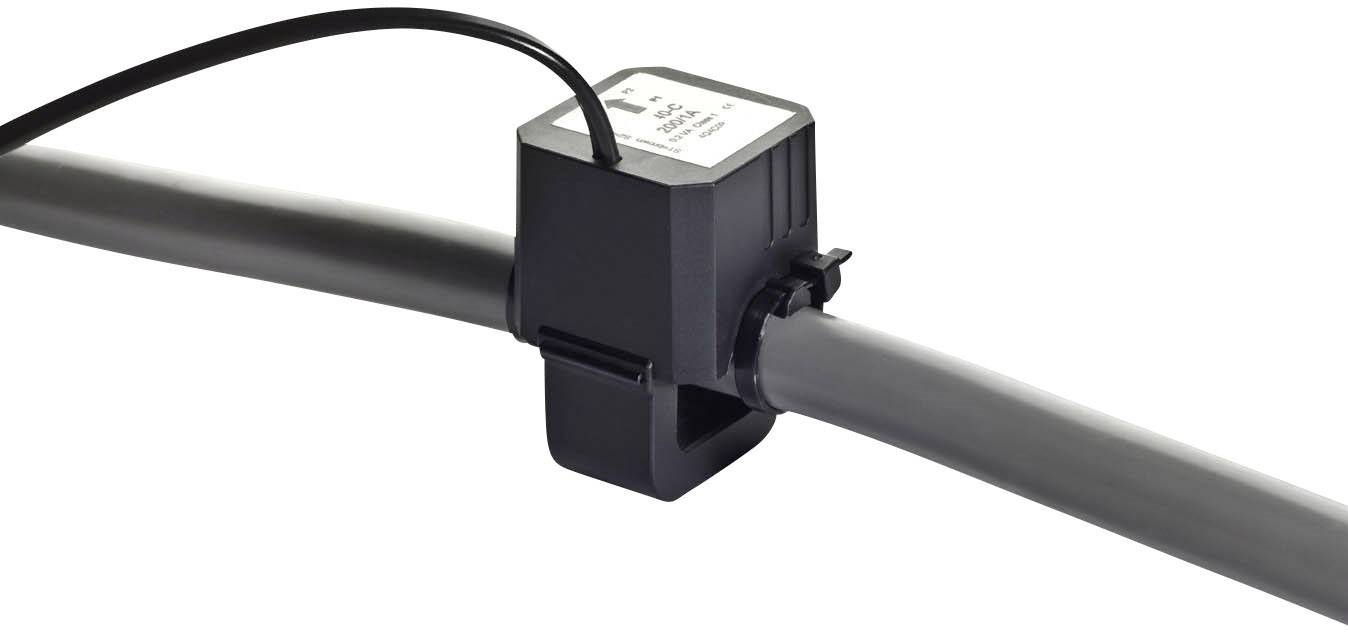 Ein schwarzer Sensor ist an einem grauen Rohr befestigt, das horizontal verläuft. Ein Kabel führt aus dem Sensor heraus.