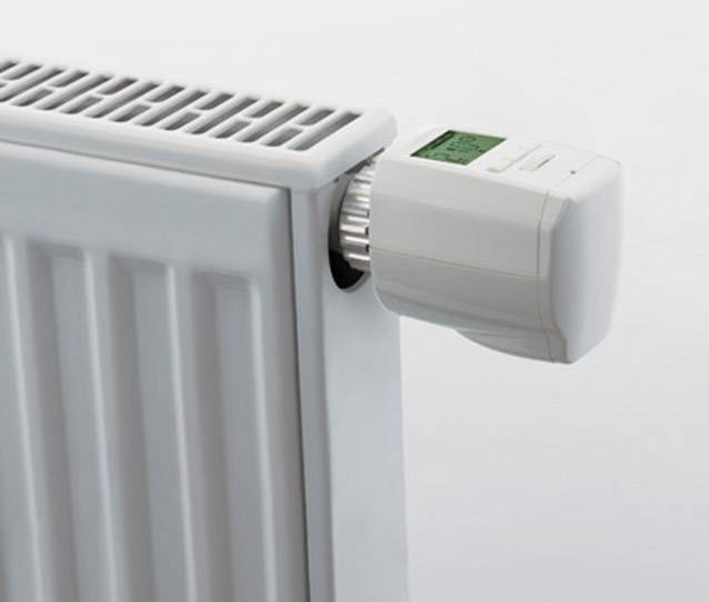 Ein weißer Heizkörper mit digitalem Thermostatregler zeigt die aktuelle Raumtemperatur an.