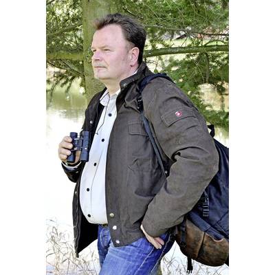 Eine Person in Freizeitkleidung steht im Freien, hält ein Fernglas und trägt einen Rucksack. Im Hintergrund sind Bäume und Wasser.