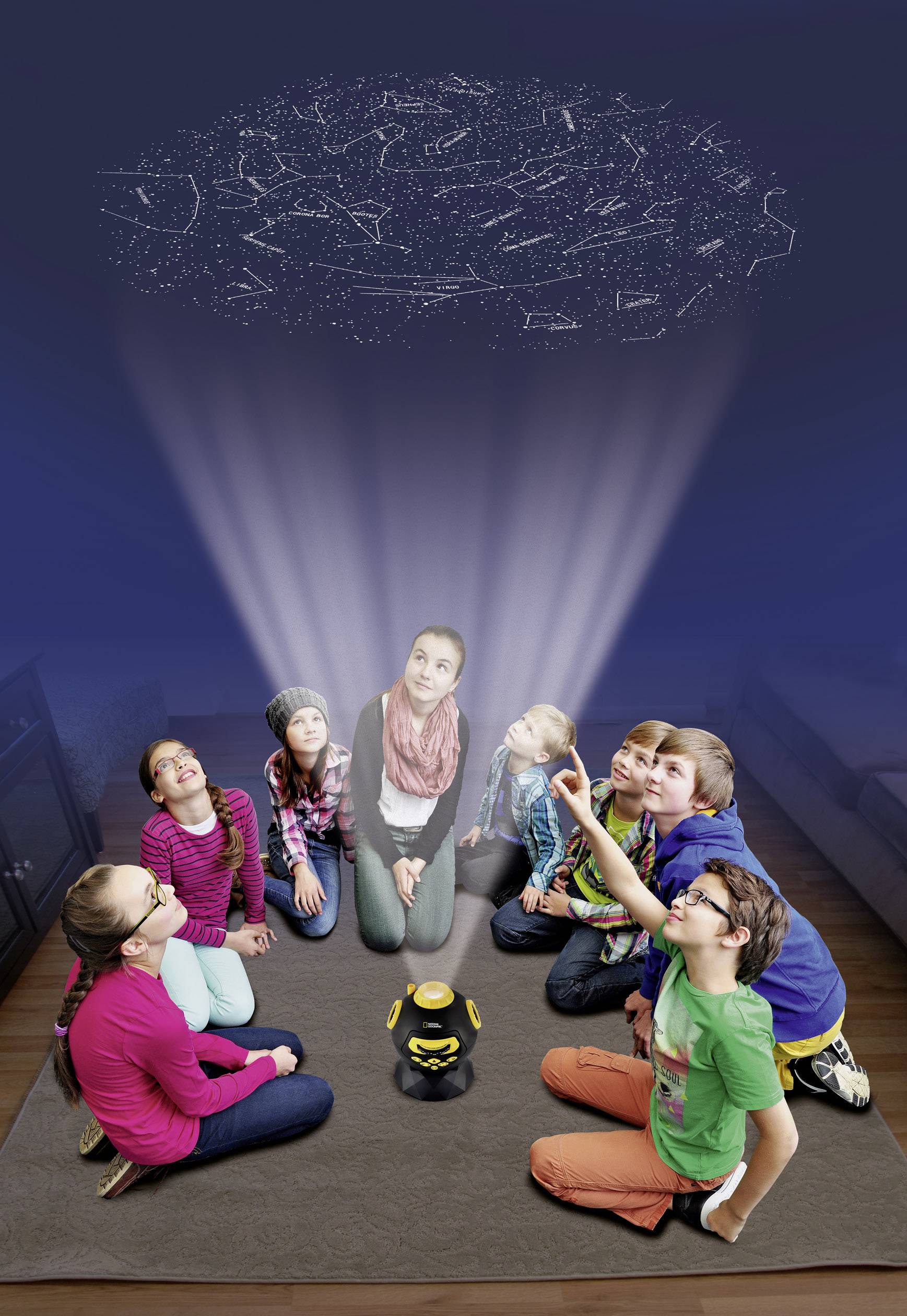 Kinder sitzen im Kreis und schauen gespannt auf ein projiziertes Sternenbild an der Decke. Eine Lampe in der Mitte strahlt das Bild aus.