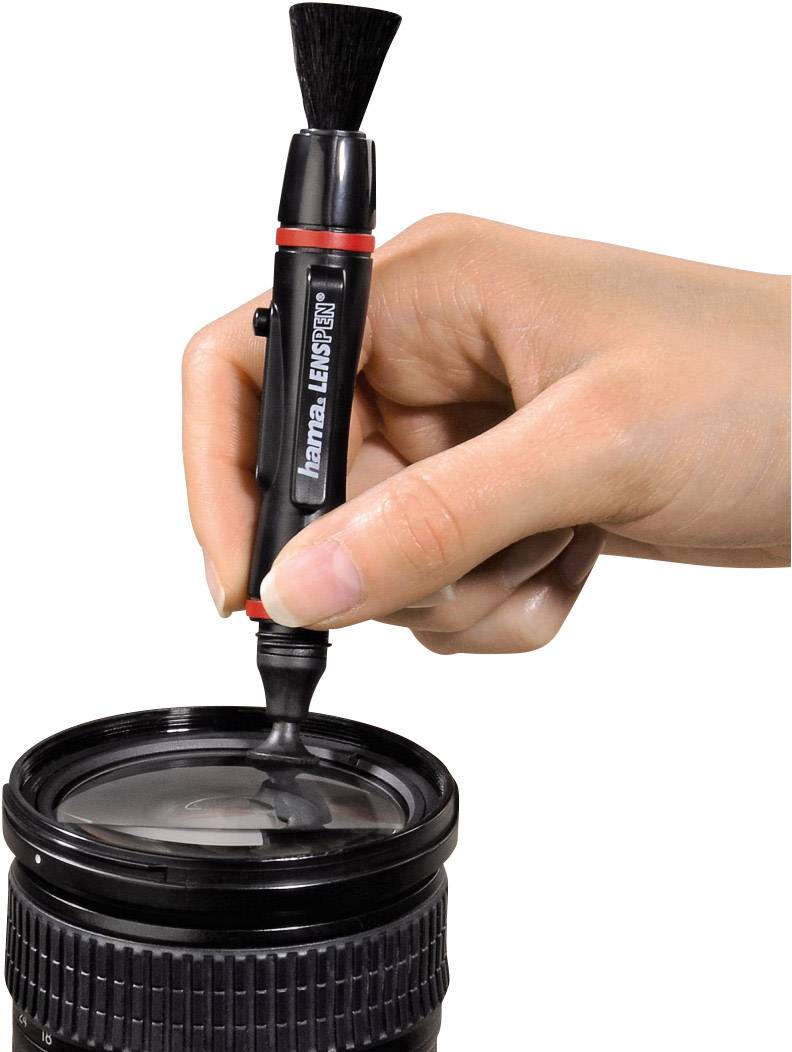 Eine Hand reinigt mit einem speziellen Pinsel die Glaslinse eines Kameraobjektivs.