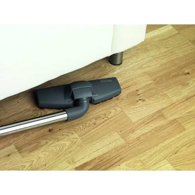 Ein Staubsauger reinigt den Holzboden unter einem weißen Sofa, um Staub und Schmutz zu entfernen.
