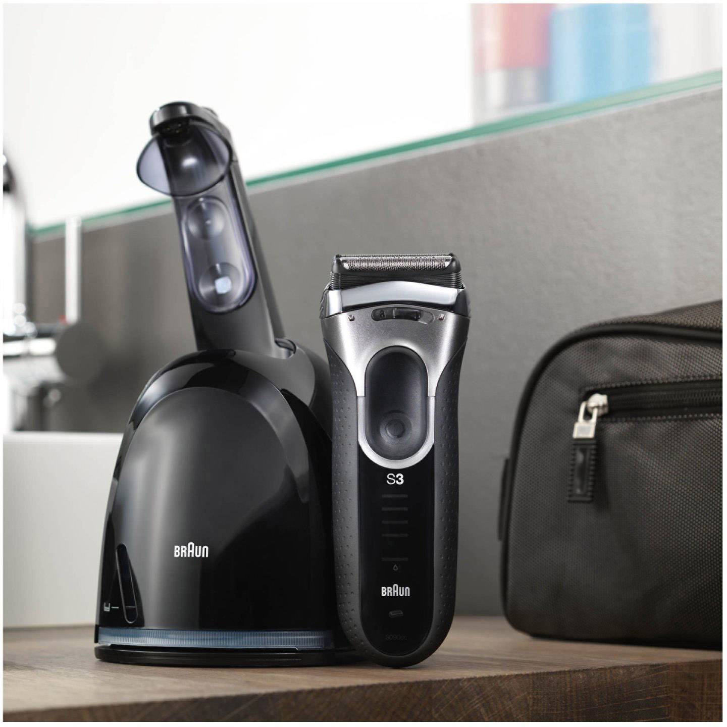 Elektrorasierer von Braun auf einer Ladestation in einem Badezimmer, neben einer kleinen schwarzen Kosmetiktasche.