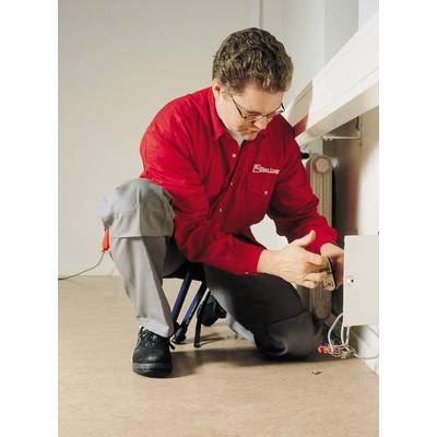 Ein Techniker in rotem Hemd und grauer Hose arbeitet an einer elektrischen Box an der Wand.