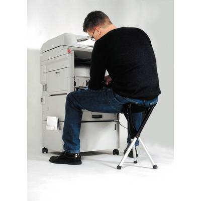 Ein Mann sitzt auf einem Hocker und bedient einen Kopierer.
