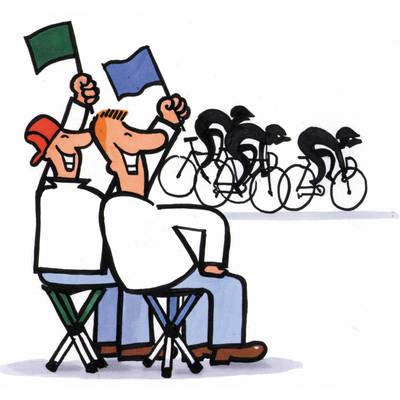 Zwei Männer schwenken Fahnen, während Rennradfahrer in einem Wettkampf vorbeifahren. Die Szene zeigt eine fröhliche Atmosphäre.