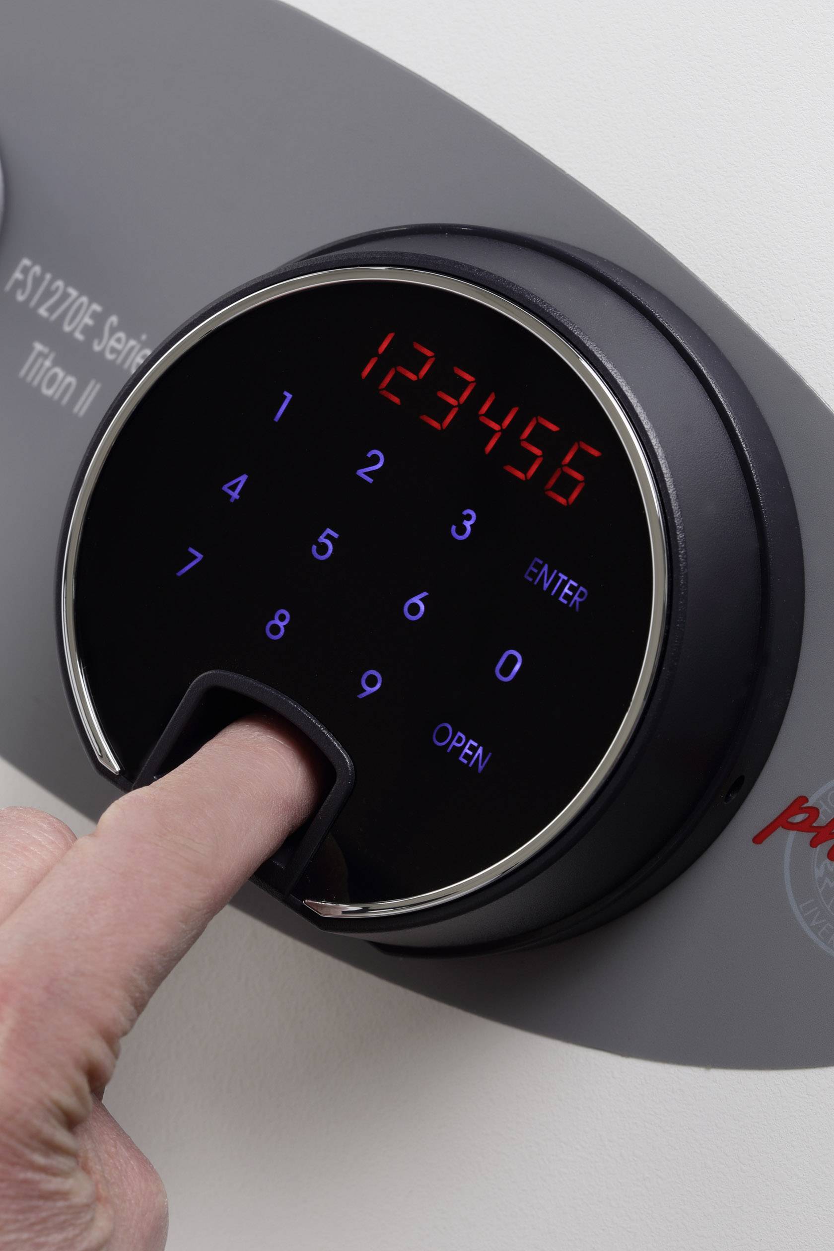 Eine Person legt den Finger auf einen digitalen Tresor mit leuchtender Tastatur. Der Tresor zeigt die Zahlen '123456'.