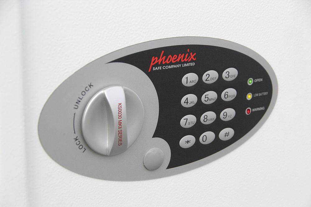 Schlosspanel eines Sicherheitssafes mit Zahlentastenfeld und Drehknopf, Markierung für 'LOCK' und 'UNLOCK', Firmenname oben.