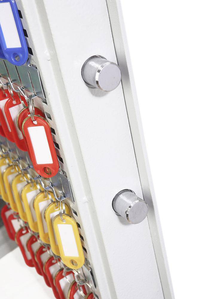 Schrank mit zahlreichen bunten Schlüsseln an Metallhaken, im Detail dargestellt.