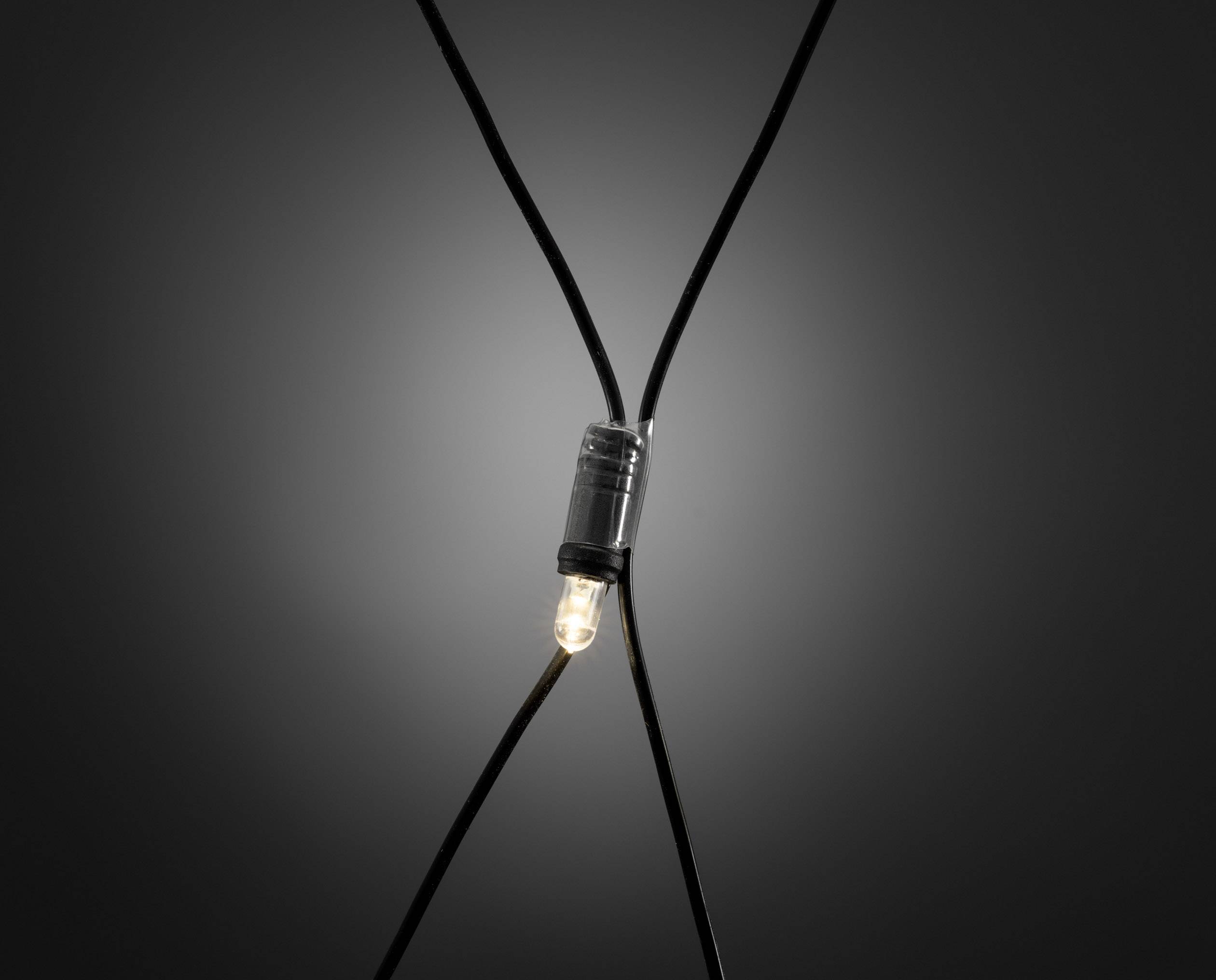 Ein einzelnes glühendes Licht, das an einem schwarzen Kabel hängt, vor einem dunklen Hintergrund.