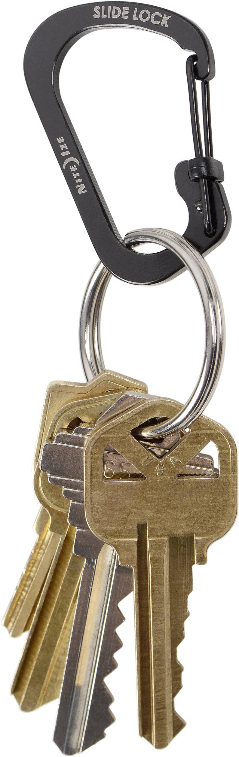 Ein Karabinerhaken mit der Aufschrift 'Slide Lock', an dem mehrere goldene Hausschlüssel hängen.