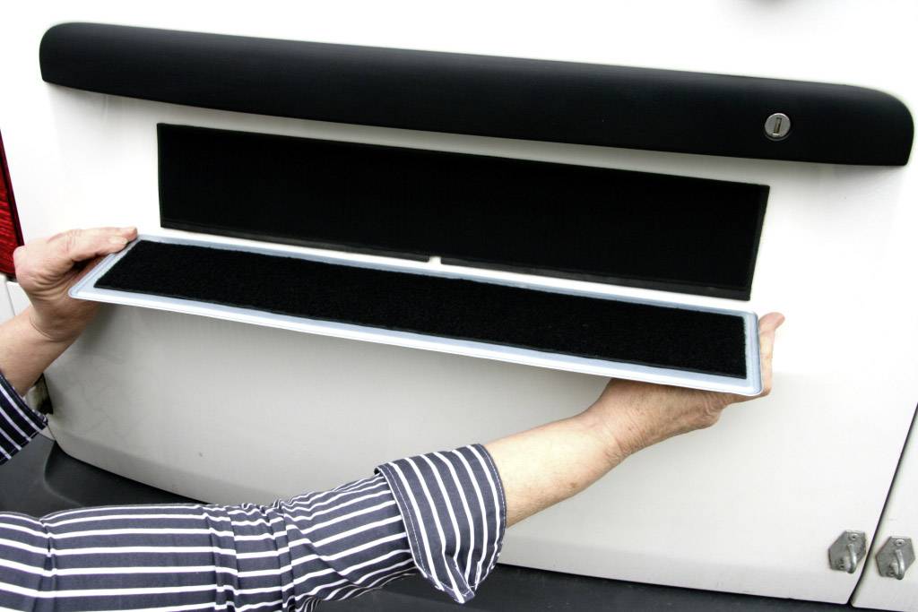 Zwei Hände halten ein rechteckiges Schild mit einem schwarzen Bereich vor einem weißen Hintergrund.