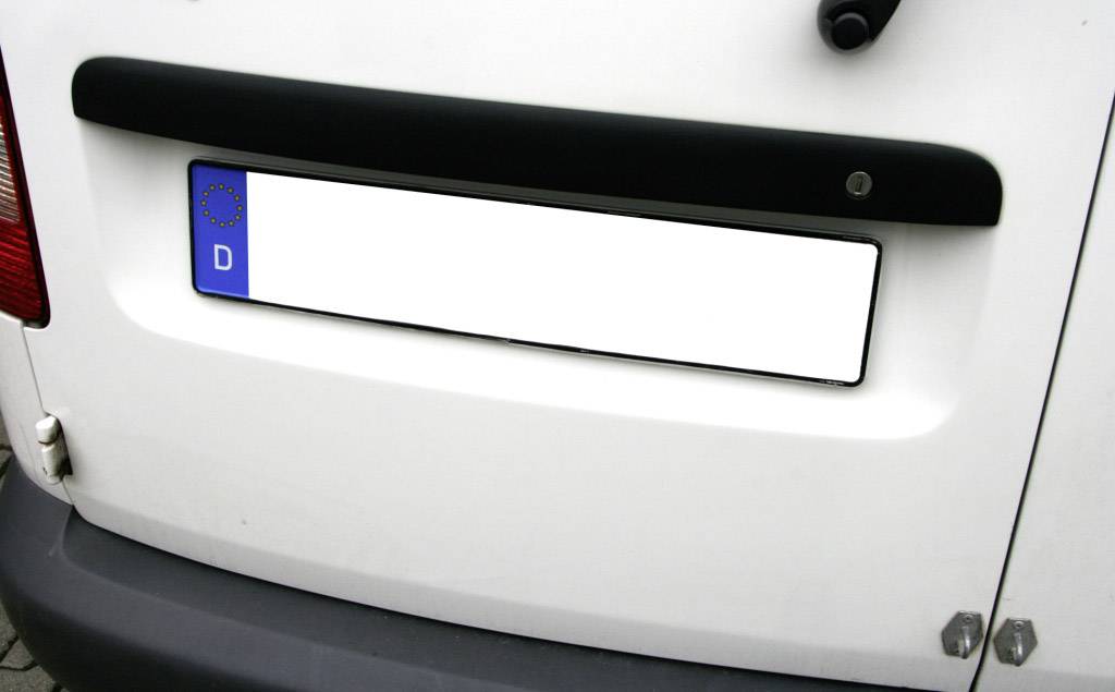 Das Bild zeigt ein deutsches Kfz-Kennzeichen auf einem weißen Fahrzeug. Es hat das blaue EU-Symbol mit dem Buchstaben 'D'.