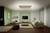 Ein modernes Wohnzimmer mit weißem Sofa, grünem Akzent an der Wand, Flachbildfernseher, Teppich und dekorativen Kissen.