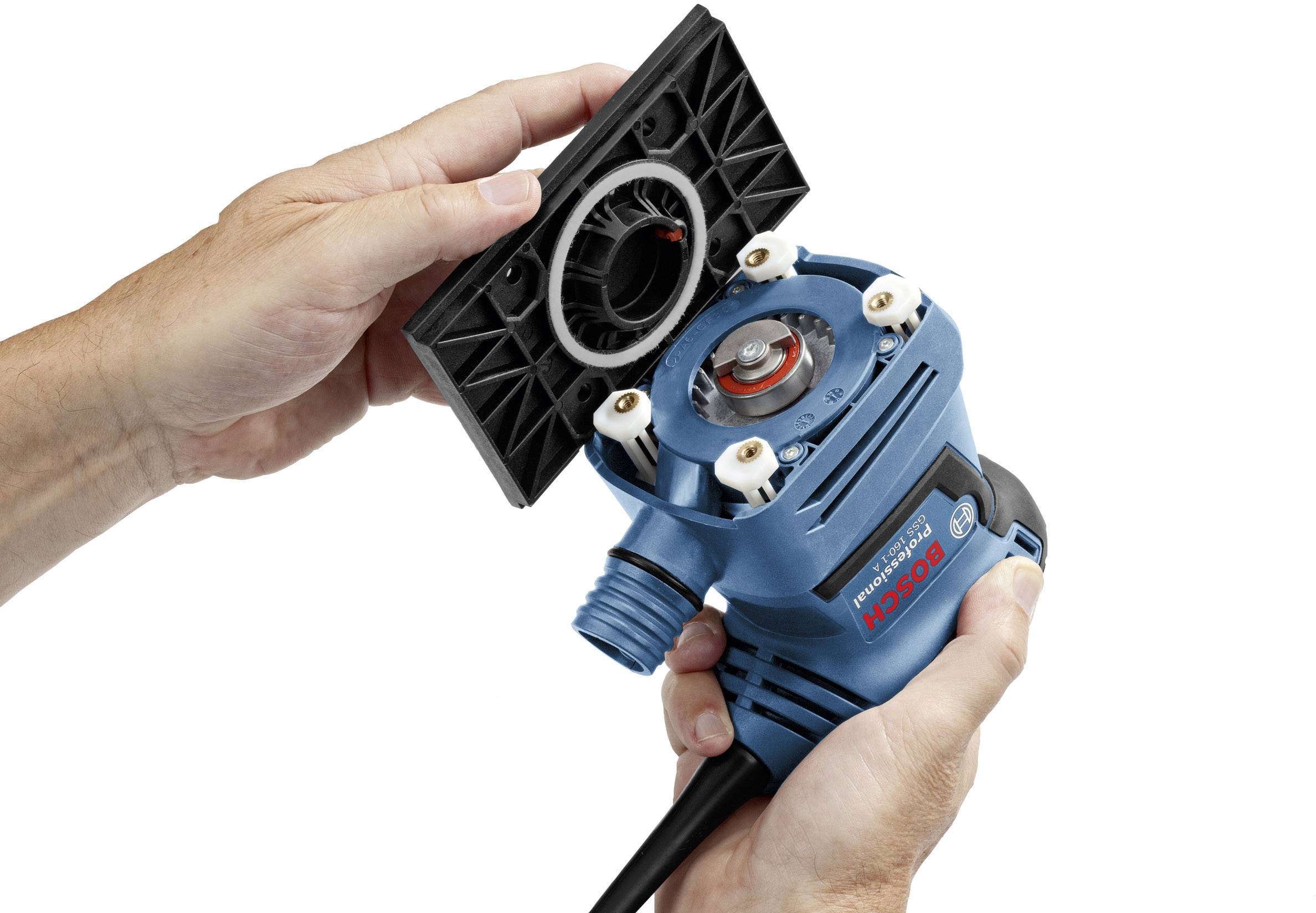 Eine Person hält eine blaue elektrische Oberfräse und setzt eine schwarze Bodenplatte ein.