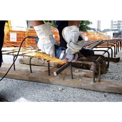 Eine Person in Handschuhen schneidet mit einem Winkelschleifer Eisenstäbe auf einer Baustelle. Funken sprühen vom Werkzeug.