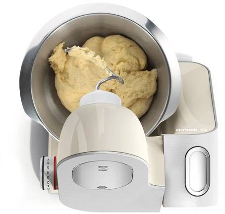 Ein Küchenmixer mit Teighaken knetet einen hellen Teig in einer Metallschüssel.