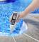 Eine Hand hält ein digitales pH-Messgerät über einem blauen Pool, um den Wasser-pH-Wert zu überprüfen.