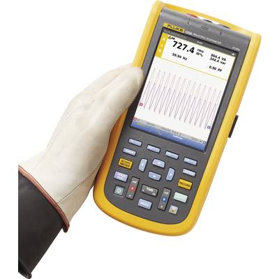Hand hält ein gelbes tragbares Gerät mit Display, das Messdaten anzeigt, darunter Frequenzen und Spannung. Das Gerät ist handgroß.