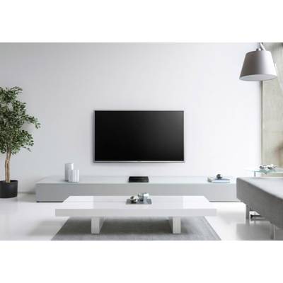 Ein modernes Wohnzimmer mit einem Flachbildfernseher an der Wand, einem weißen niedrigen Tisch und einer Pflanze in der Ecke.