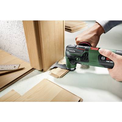Eine Person schneidet mit einem Multifunktionswerkzeug ein Stück Holz in Bodennähe, um Platz für den Bodenbelag um einen Türrahmen zu schaffen.