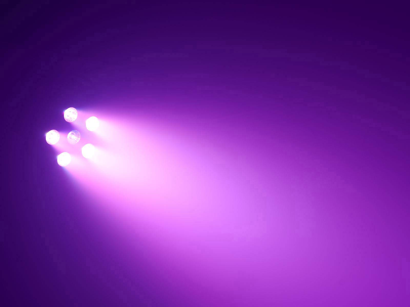 Vier Scheinwerfer leuchten in einem dunklen Raum, erzeugen einen lila Lichtstrahl.