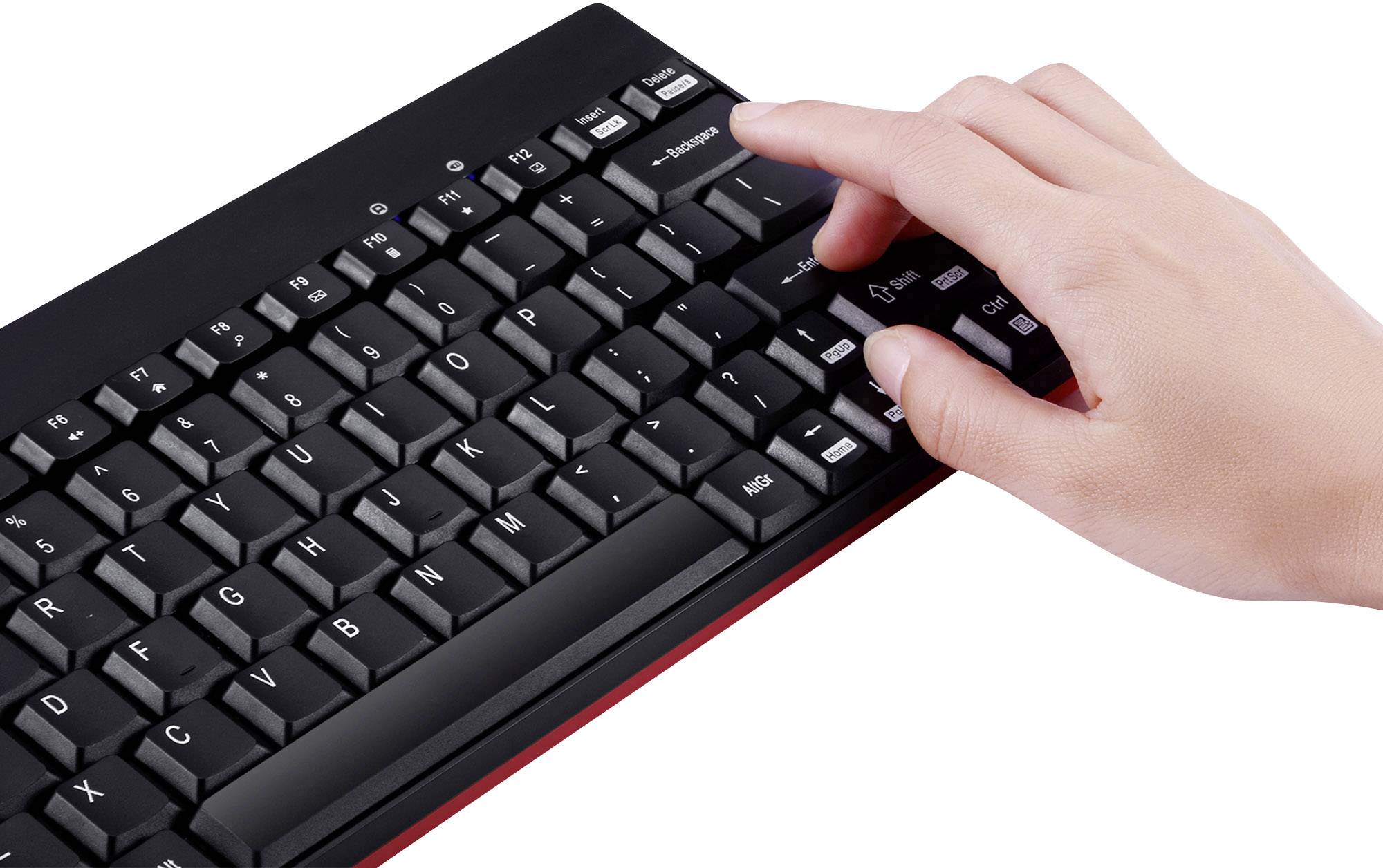 Hand drückt die Eingabetaste auf einer schwarzen Tastatur mit roten Akzenten.