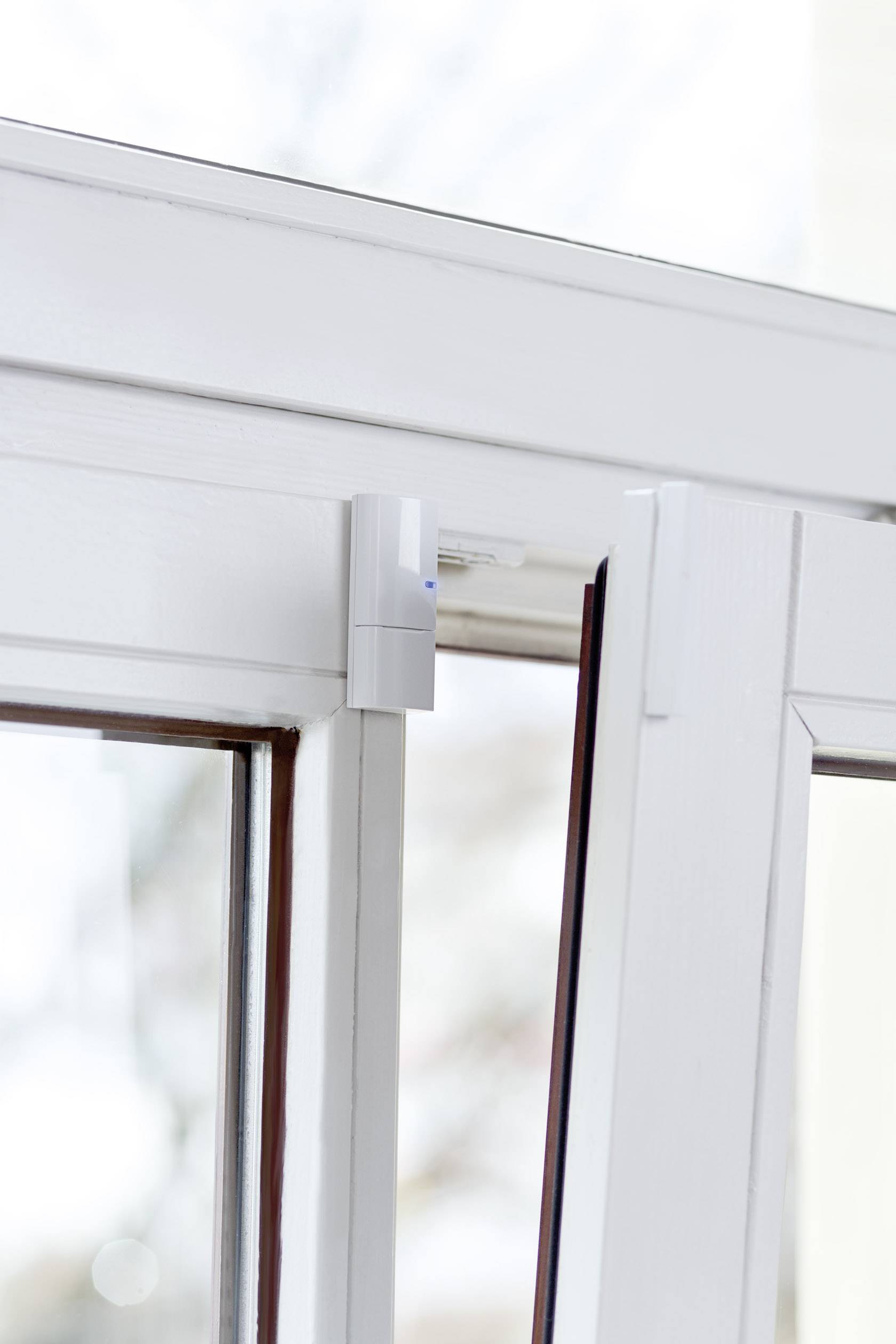 Ein Fenster mit einem Sicherheitssensor an der Ecke befestigt. Der Sensor überwacht die Öffnung des Fensters zur Einbruchsicherung.