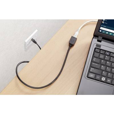Ein Laptop auf einem Tisch ist mit einem Netzkabel mit einer Steckdose verbunden. Der Bildschirm zeigt ein Windows-Betriebssystem.