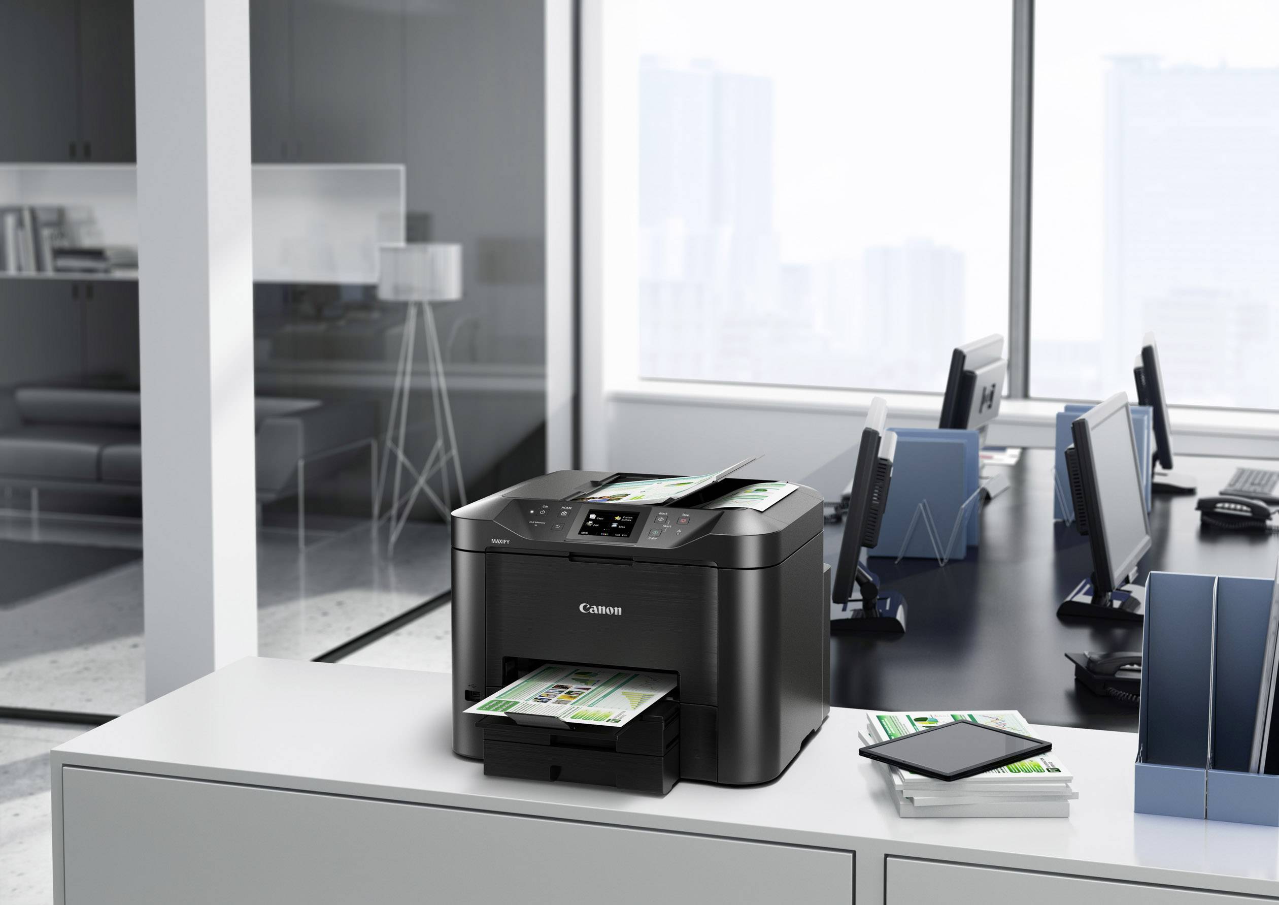 Ein Drucker auf einem modernen Büroschreibtisch druckt farbige Dokumente. Im Hintergrund sind Computerarbeitsplätze sichtbar.